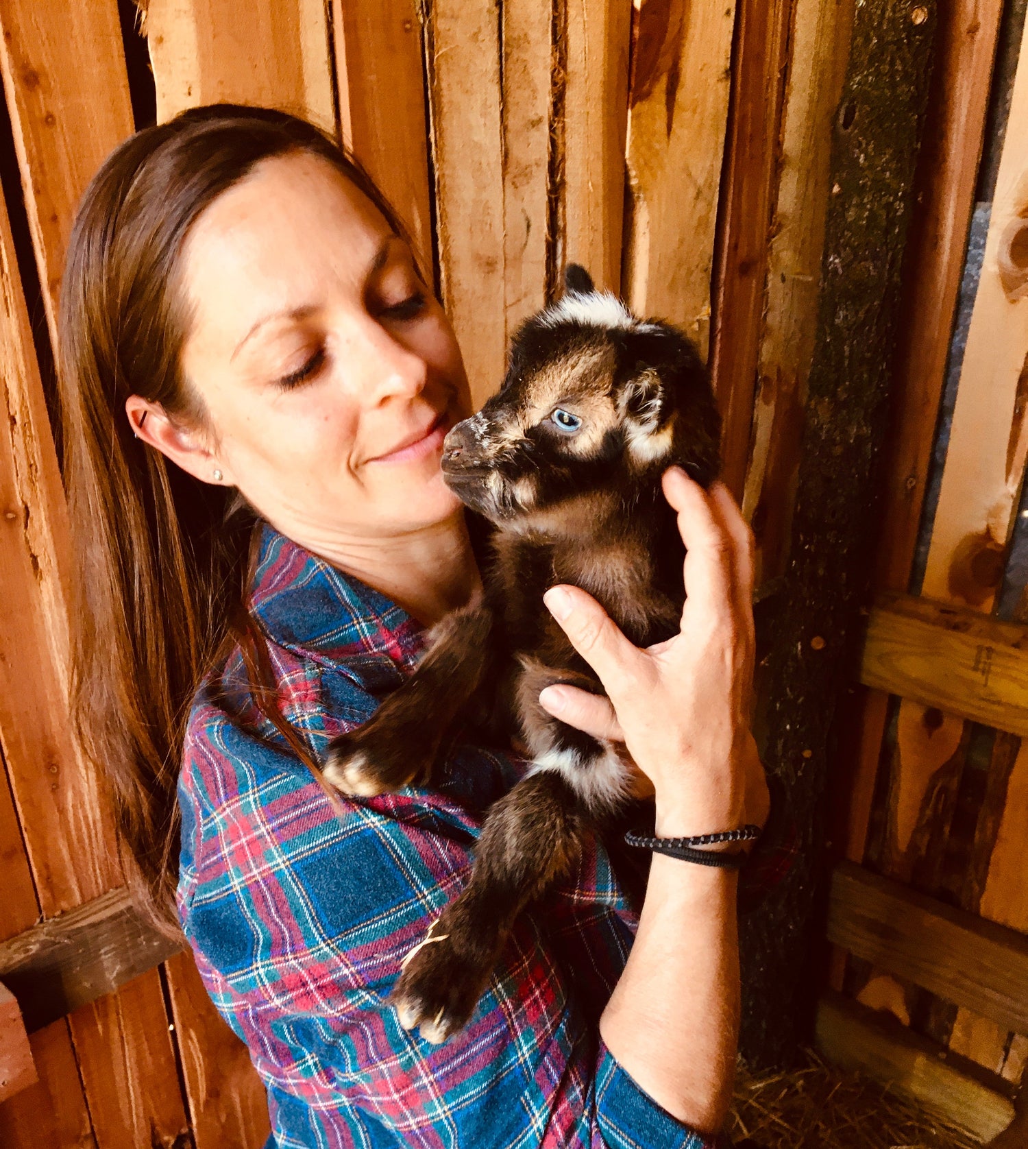 Woman holding a baby goat inside a barn